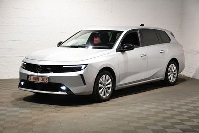 La voiture blanche est garée dans une pièce blanche au sol à carreaux.