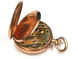 a gold pocket watch that is open on a white surface