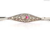 a close up of a silver bracelet with a pink stone in the center