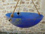 a blue bowl hanging from a rope near a stone wall