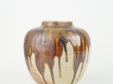 un vase brun et blanc posé sur une surface blanche