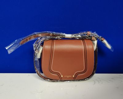 un petit sac à main marron muni d'une poignée en plastique transparent, posé sur une table
