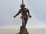 une image représentant une statue en bronze d'un homme tenant une lampe