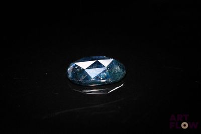 a close up of a blue diamond on a black surface