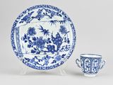 a blue and white plate with a cup and saucer on a stand