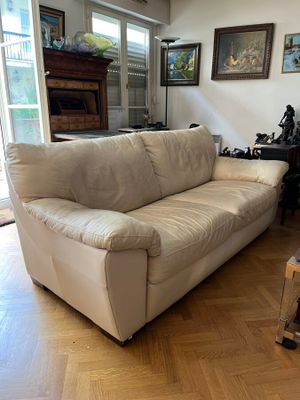 un canapé blanc placé dans un salon, près d'une fenêtre