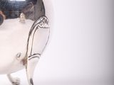 a silver tea pot with a handle on a stand