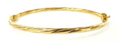 gros plan d'un bracelet en or sur une surface blanche