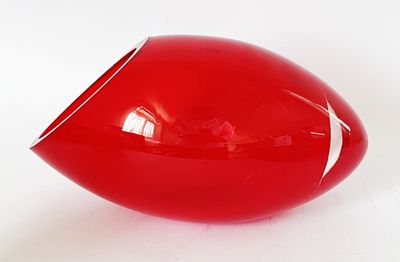 un vase rouge posé sur une surface blanche
