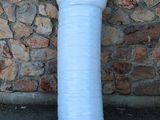 un grand vase blanc posé par terre près d'un mur de pierre