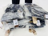 many pieces of clothing wrapped in plastic on a table