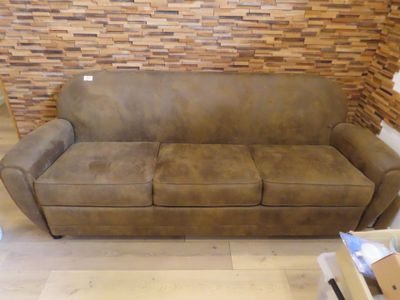 a couch that is sitting in a room with a brick wall behind it