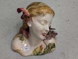 une tête de femme en céramique, avec une fleur dans les cheveux