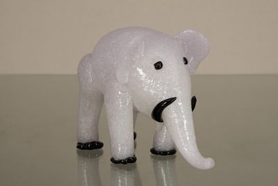 une petite figurine d'éléphant blanche posée sur une surface brillante