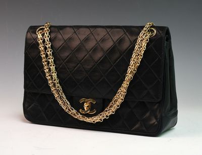 un sac Chanel noir orné de chaînes dorées sur fond blanc