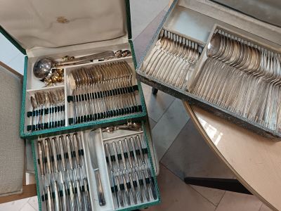 des couverts dans un étui vert posé sur une table à côté d'un plateau à couverts