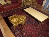 Une personne se tient dans un salon où se trouvent un tapis et une table basse.