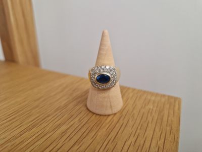 bague en argent et pierre bleue posée sur un cône en bois, lui-même posé sur une table en bois