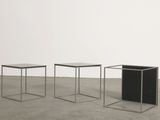 three black and white tables sitting on top of a cement floor