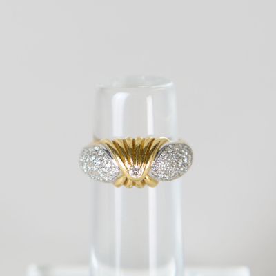 un gros plan d'une bague en or et diamants posée sur un verre