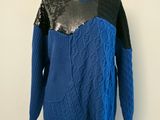 Le pull est bleu et noir, avec des paillettes.