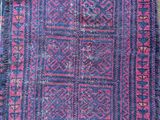 a blue and pink rug on a wooden floor next to a wall
