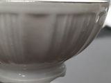a white bowl sitting on top of a table next to a knife