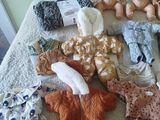 a lot of baby clothes and dolls on a bed