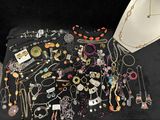 many different necklaces and bracelets displayed on a table