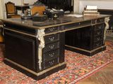 a black desk with a marble top in a room with a fireplace
