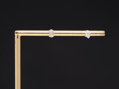 a pair of diamond stud earrings on a gold bar