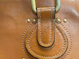 an image of a brown purse with a metal ring on the handle