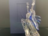 une photo d'une figurine en verre représentant une femme assise sur une table
