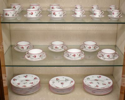 de nombreuses tasses et soucoupes sur les étagères du vaisselier