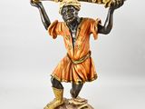une image représentant une statue d'un homme tenant un plateau sur la tête