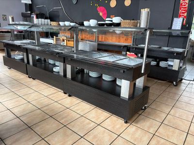 sol carrelé dans un restaurant où se trouve une longue table de buffet sur laquelle sont disposées des assiettes et des bols