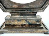 a silver clock sitting on top of a wooden stand
