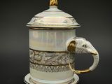 une tasse à café blanche et dorée ornée d'une tête d'éléphant