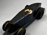 une petite voiture noire avec un chien à l'avant