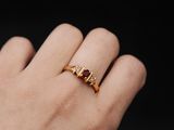 La femme porte une bague en or sertie d'un rubis.