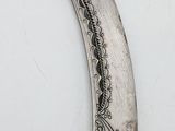 a silver knife with a design on it on a white surface