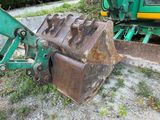 a green excavator that is sitting on the ground