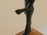 une statue représentant une femme tenant un oiseau, posée sur un socle en bois
