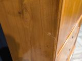 a wooden cabinet with three drawers sitting on top of a tiled floor