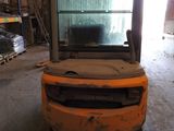 a forklift in a warehouse with pallets in the background