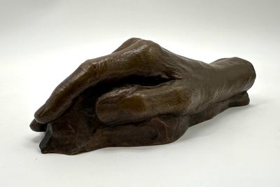 statue of a hand holding a piece of wood on a white surface