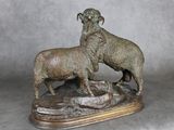 statue représentant un bélier et une brebis posés sur un rocher, sur fond gris