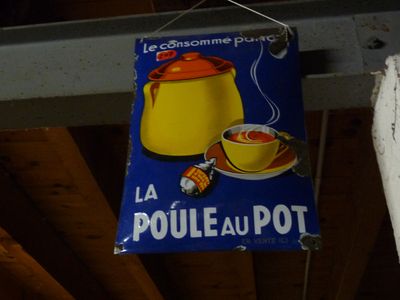 une enseigne accrochée sur la façade d'un immeuble sur laquelle on peut lire « La Poule au Pot »