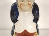 a ceramic figurine of a man wearing a hat and red pants