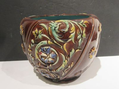 a brown and green vase sitting on a white table